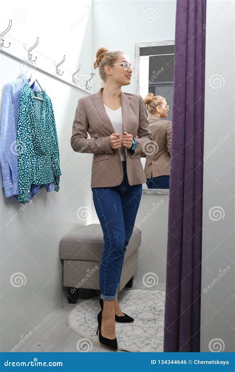 Young Woman Trying On Clothes In Dressing Room And。